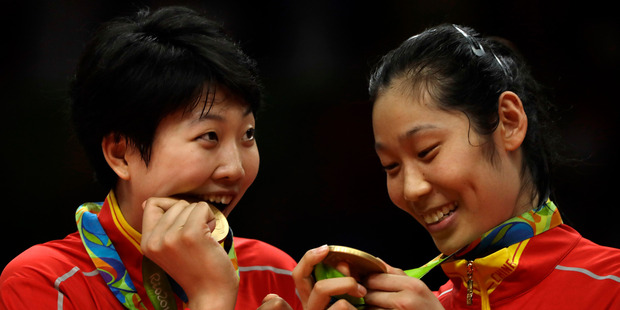 China's Yuan Xinyue, left, bites her gold medal as Zhu Ting examines hers during an awarding ceremony for women's volleyball at the 2016 Summer Olympics. Photo / AP