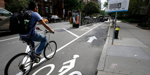 Cyclist enters a bike lane that is routed between parked cars and the sidewalk in Boston. Photo / AP
