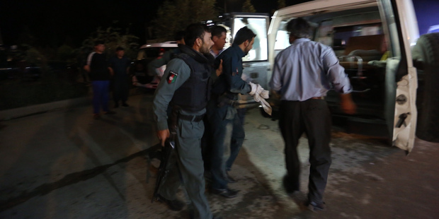 An Afghan policemen wounded in a Taliban attack on the university is helped to an ambulance. Photo / AP