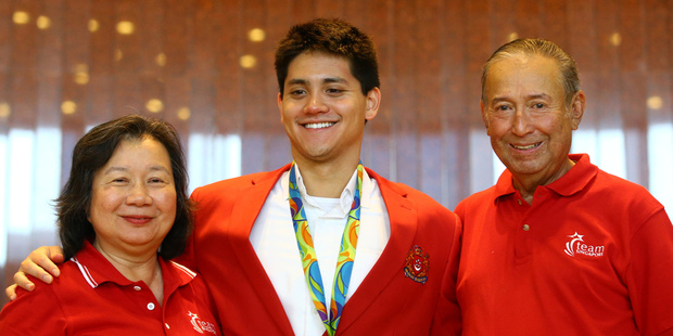Singaporean swimmer Joseph Schooling, centre, poses with his parents after winning a gold medal and one million Singaporean dollars. Photo / AP