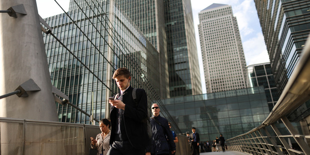 Pedestrians cross a raised walkway in the Canary Wharf financial business district in London. Photo / Simon Dawson