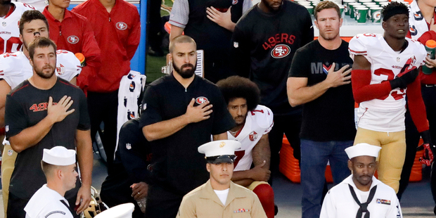 San Francisco 49ers quarterback Colin Kaepernick, middle, kneels during the national anthem before the team's NFL preseason football game against the San Diego Chargers. Photo / AP