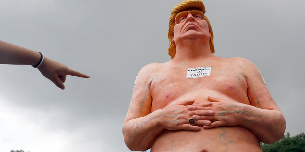 A woman points at a statue of a naked Republican presidential candidate Donald Trump in New York. Photo / AP
