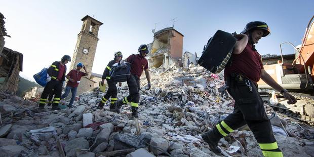 Firefighters carry personal belongings retrieved from houses, in Amatrice, central Italy. Photo / AP