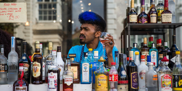 A barman has a drink behind a pop-up bar at the Notting Hill Carnival. Photo / Getty