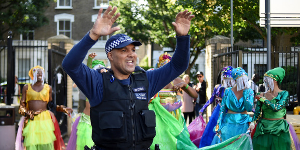 A police officer dances with a group of performers during the Notting Hill Carnival on August 29, 2016 in London, England. Photo / Getty
