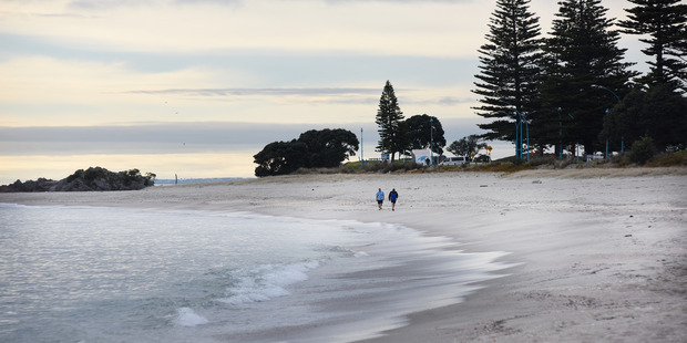 Early morning walkers still hit the beach after tsunami warning was issued yesterday morning. Photo/George Novak