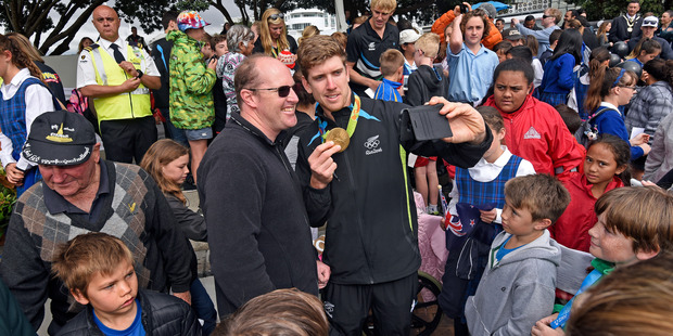 Sailor Peter Burling takes selfies with the crowd at the Olympic parade in the city centre. Photo/George Novak