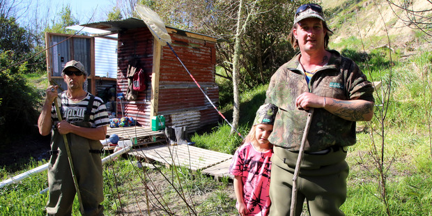 Bradie Alabaster, 39, his daughter Taylor and friend Curtis Parker in front of the whitebaiting hut on Upokongaro Creek. Photo/Stuart Munro