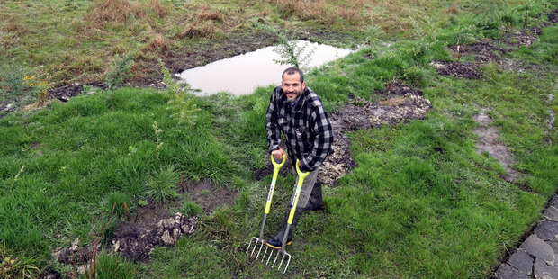 Nelson Lebo loosens compacted soil in preparation for organic gardening.
