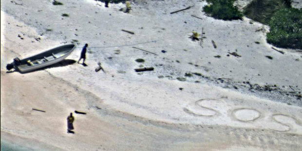 A pair of stranded mariners signal for help by writing SOS in the sand as a US Navy P-8A Poseidon aircraft crew from Patrol Squadron (VP) 8 flies over. Photo / US Navy