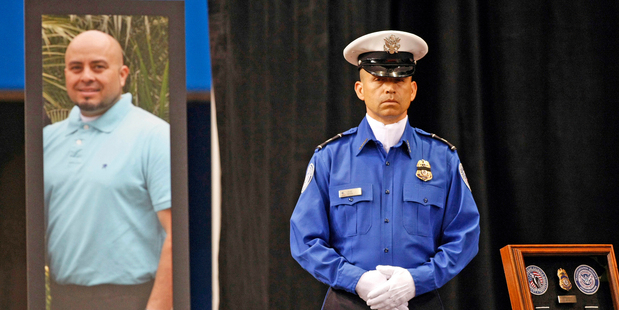 A Transportation Security Administration officer stands in front of a portrait of slain TSA officer Gerardo Hernandez during his public memorial in 2013. Photo / AP