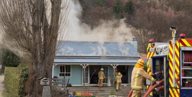 Firefighters work to contain a fire at a Criterion St home in Arrowtown yesterday, which appeared to have started in the roof. Photo / Otago Daily Times / Blair Pattinson