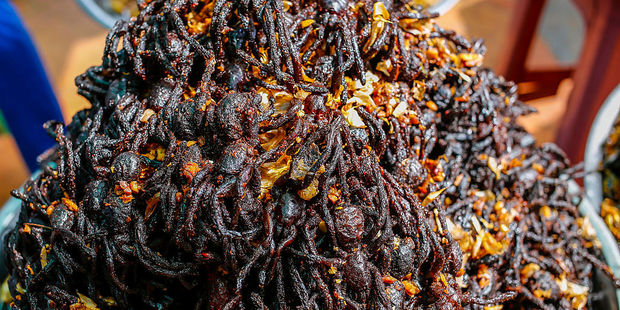 The arachnids are now becoming a tasty snack - deep fried and served with a pinch of herbs on a bed of noodles or rice. Photo / Getty Images