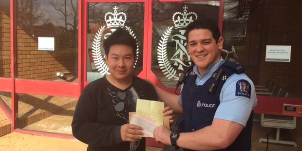 Officer in charge of the food caravan theft case Constable Isaac Teleiai hands over a $1000 donation from a member of the public to Gritsaru 'Ize' Janshinorat, the caravan owner. Photo/NZ Police