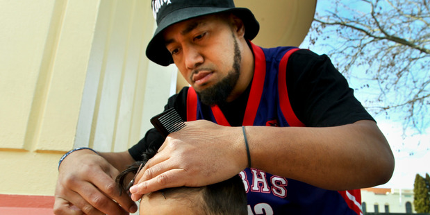 Hastings hairdresser Peleti Oli cuts Lance's hair under the town clock. Photo Warren Buckland