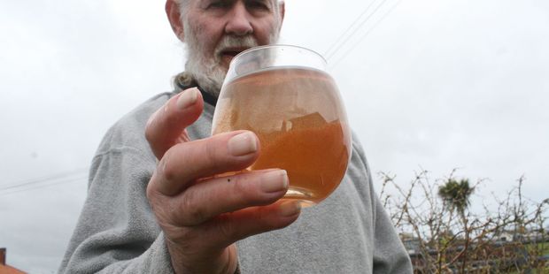 Foxton resident Bruce Mulhare holding a glass of Foxton tap water before it is processed by his filters.