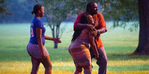 A man holds a woman at the scene of a double shooting in Ogden Park. Photo / AP