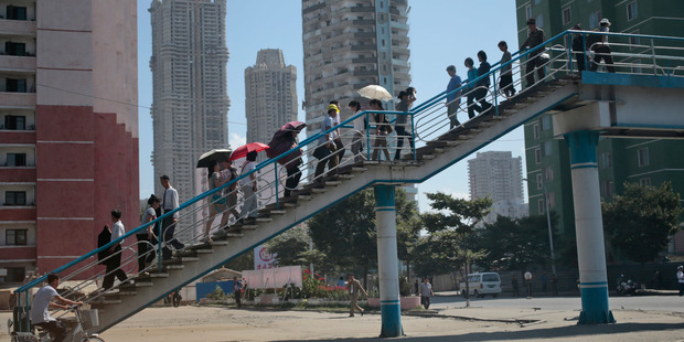 North Koreans use a pedestrian bridge to cross a road in downtown Pyongyang, North Korea. Photo / AP