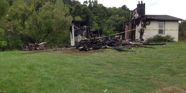 Police tape cordons off the remains of a house where authorities say a woman's body was found nearby. Photo / AP