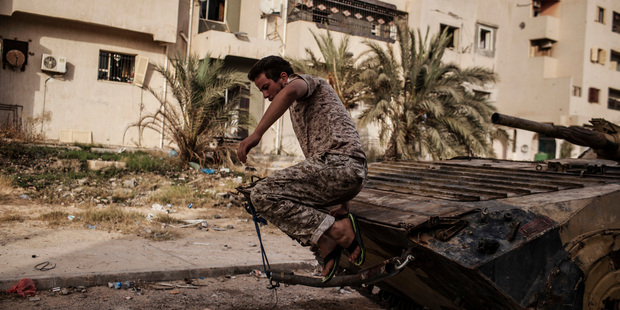 A fighter from Misrata forces jumps from atop an armoured vehicle during an operation against Isis militants in Sirte, Libya. Photo / AP