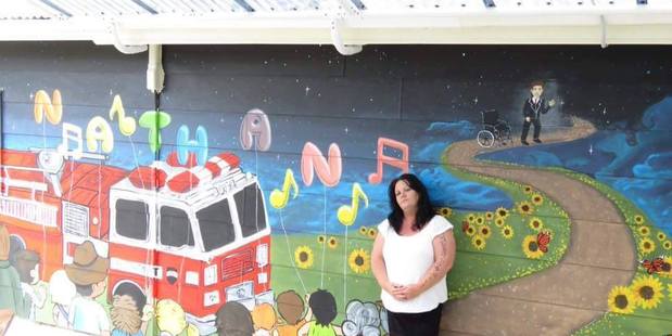 Angela Middlemiss stands in front of a mural painted in her son Nathan Booker's honour at the IHC centre in Palmerston North. High needs teen, Nathan, aged 14, drowned in a bath at Idea's Woburn Famil