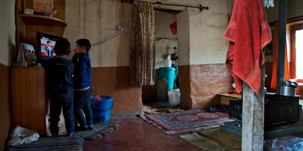 Two children watch television in the living room of their family home in Demul village, Spiti Valley, India. Photo / Thomas Cytrynowicz