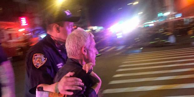 A police officer escorts an injured man away from the scene on West 23rd Street in New York. Photo / AP