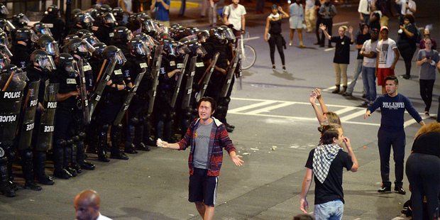 A man between Charlotte-Mecklenburg police officers and protesters in Charlotte. Photo / AP