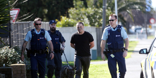 Handcuffed robber Daniel Hanley is led away by police after the Karamu Road Dairy holdup on August 28. Yesterday he pleaded guilty, facing up to 14 years' jail. Photo/File
