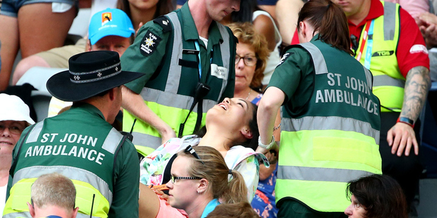 A women in the crowd is attended to by paramedics during the first round match between Bernard Tomic and Denis Istomin. Photo / Getty Images
