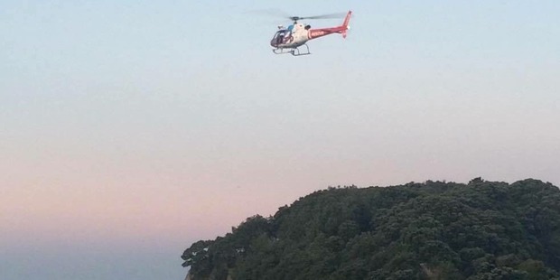 A rescue chopper searching for the teen boy after he was swept from the rocks at Mt Maunganui. Photo / Lauren Hines