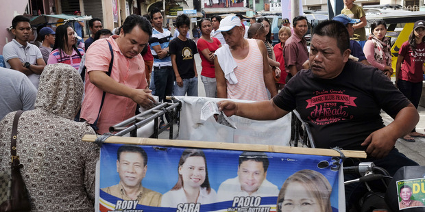 Election officials observe voters on May 9 near a polling station during the presidential elections in Davao. The cult of Rodrigo Duterte is strong in this city. Photo / Veejay Villafranca, Bloomberg
