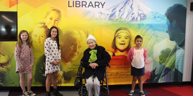 (l-r) Alex Petrie, Adelaide Petrie, Gwelfa Burgess and Coco Tihema stand by their images on the light box at Stratford Library.