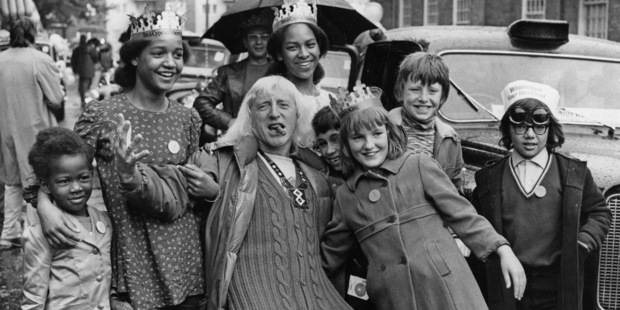 English DJ and television presenter Jimmy Savile joins a group of under-privileged and disabled children on a day out to Southend. Photo / Getty