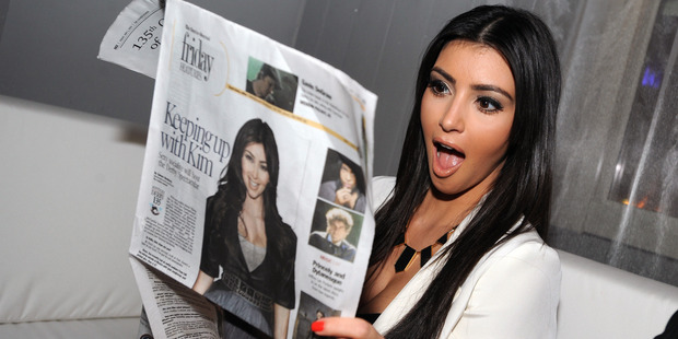 Kim Kardashian reads a Louisville Courier Journal newspaper featuring herself in 2009. Photo / Getty
