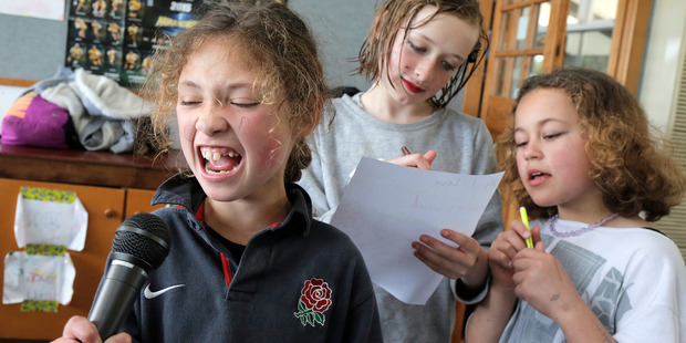 Charlotte Parks practices singing while Cheyenne Vuleta and Zyeisha Haitana write the song for a Talent Quest at the YMCA Holiday programme.