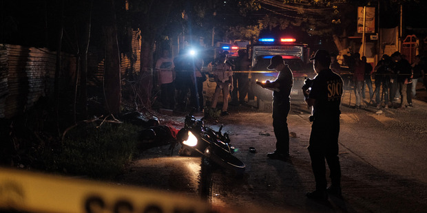Crime scene investigators examine the bodies of two suspected drug dealers that where shot dead by police in Pasig city. Photo / Washington Post