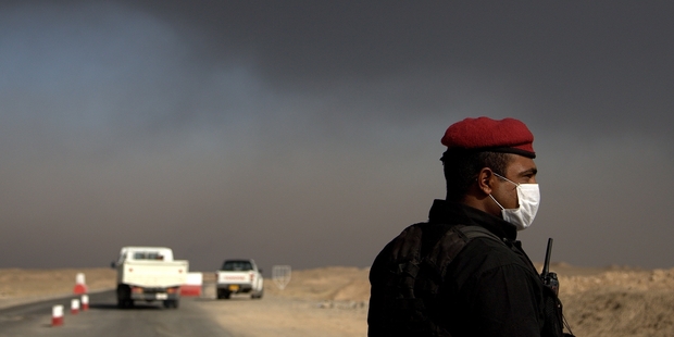 A member of the Iraqi special forces guards a checkpoint near the village of Awsaja, Iraq, as smoke fills the air. Photo / AP
