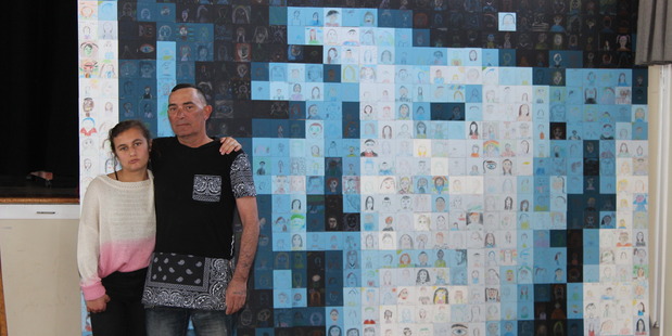 SPECIAL: Karl Farrell, with his granddaughter Taliyah Farrell, 13. Behind them is an artwork featuring hundreds of small portraits which morph into an image of Karl's mother Jean Andrews.