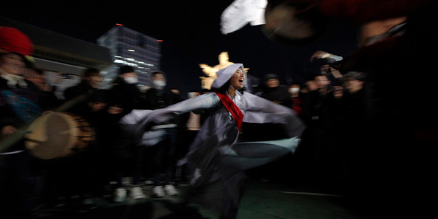 A protester satarises President Park's relationship with a sector's daughter Choi Soon-Sil wearing a costume of a shaman during a protest in Seoul. Photo / Getty