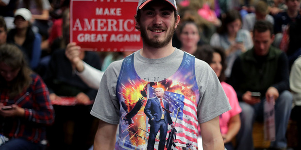 A man wears a tank top depicting Republican presidential nominee Donald Trump standing on a tank during a campaign rally. Photo / Getty Images