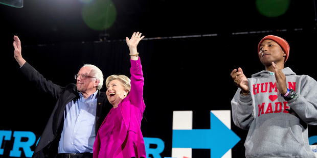Hillary Clinton and Bernie Sanders, accompanied by performer Pharrell Williams, appear on stage at a rally. Photo / AP