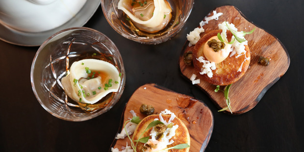 Two of the yum char dishes: the duck broth tortellini served in a small glass and the kahawai fritter served on a small wooden coaster. Photo / Getty Images