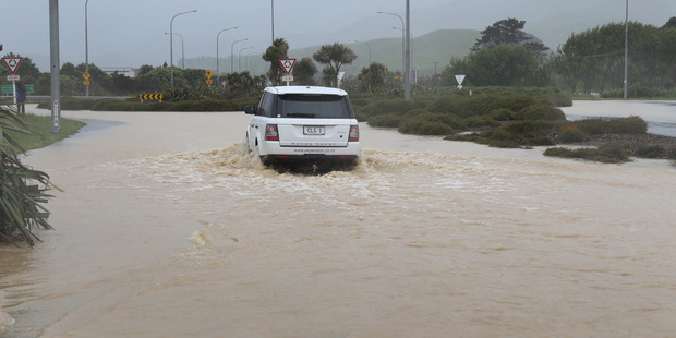 A vehicle negotiates floodwaters across State Highway One at the Plimmerton Roundabout north of Wellington on Tuesday. Photo/Mark Mitchell.