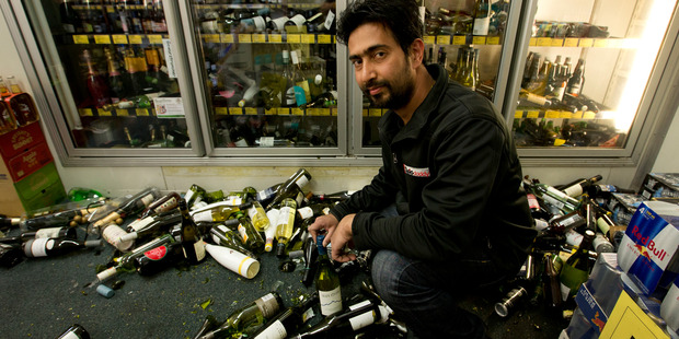 Rahul Bhandari amongst the dozens of destroyed bottles of alcohol in his bottle store located in the main street of Kaikoura. New Zealand Herald Photograph by Alan Gibson.