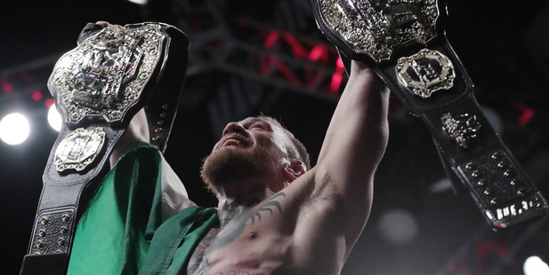 Conor McGregor holds up his title belts after he defeated Eddie Alvarez during their lightweight title. photo / AP