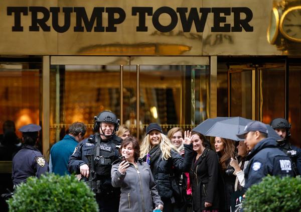 Passersby stop for a selfie with a heavily-armed New York City police officer at the main, Fifth Avenue entrance to Trump Tower. Photo / AP