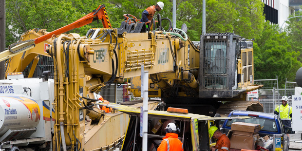 Workers assembling the boom on the 85-ton ultra-high-reach excavator that will to be used to demolish Wellington's 61 Molesworth St. Photo / Mark Mitchell