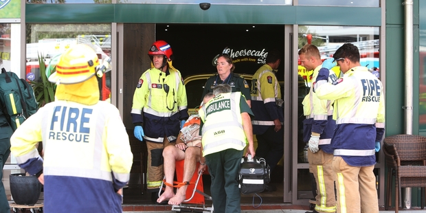 St John staff help the driver of a car that ended up inside a shop, trapping a mother and daughter in a cake cabinet. Photo / Michael Cunningham